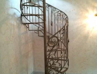 Scala a chiocciola in ferro con struttura  pedate e  balaustra floreale 