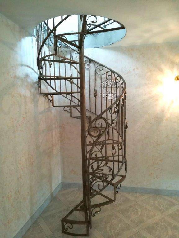 Scala a chiocciola in ferro con struttura  pedate e  balaustra floreale 